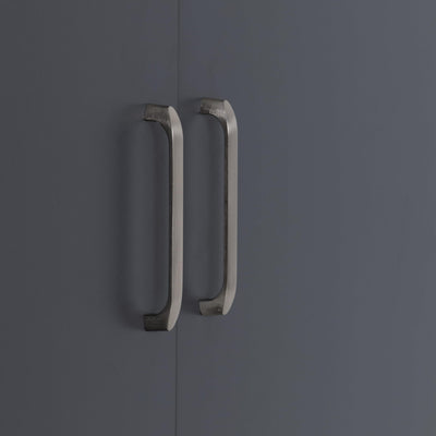 Close-up of two brushed metal vertical handles mounted on dark grey wardrobe doors