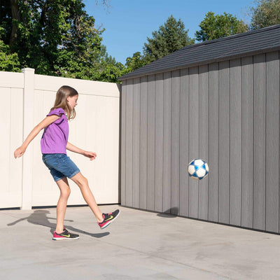 Three-quarter view of the 8×12.5 ft storm dust grey storage shed on a concrete pad next to lawn and flowerbed.