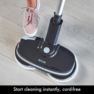 Foot pressing the PowerGlide's top release/power button on the base while standing on a tiled floor