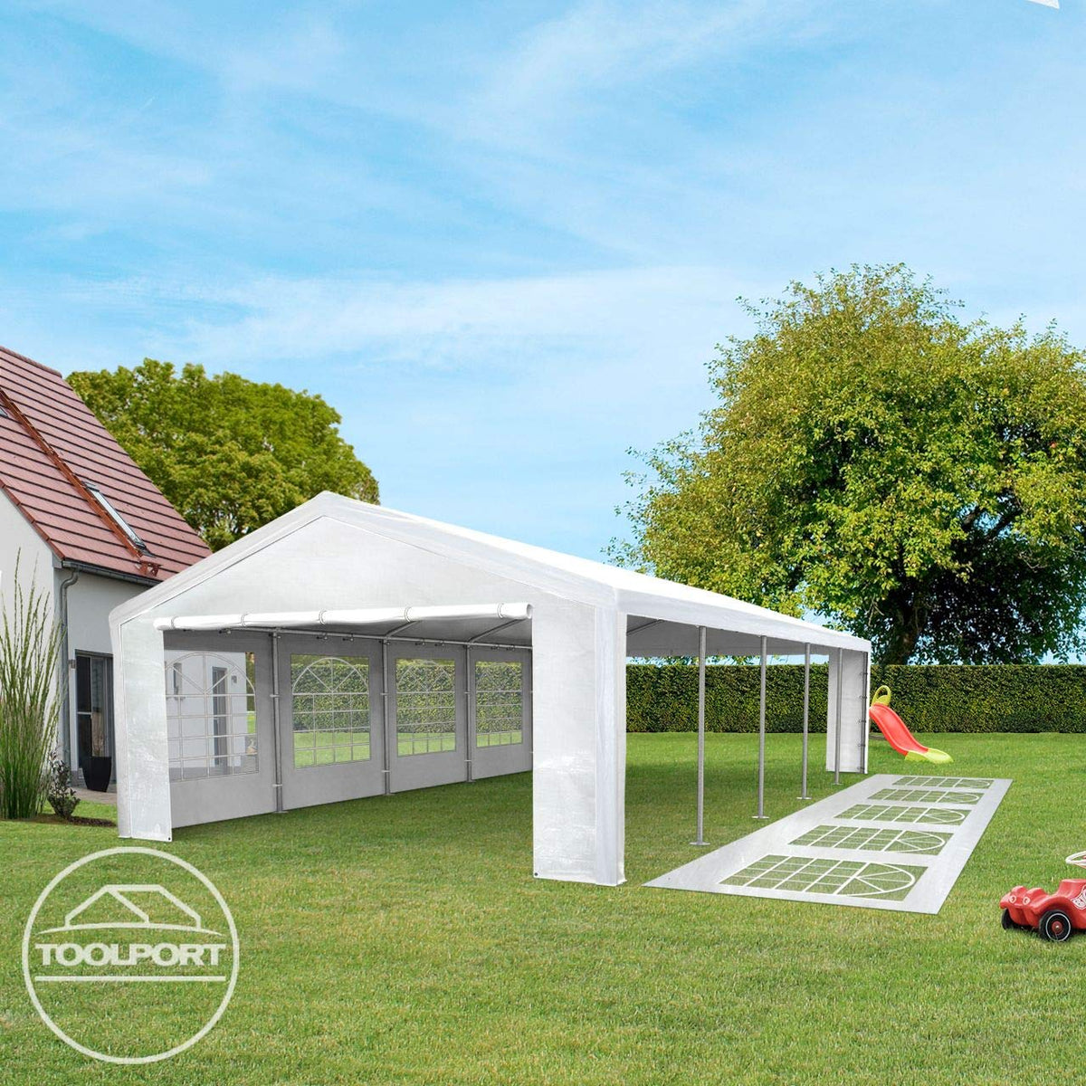 Angled view of marquee with an open side, spare window panels laid on the lawn and children's toys at the edge