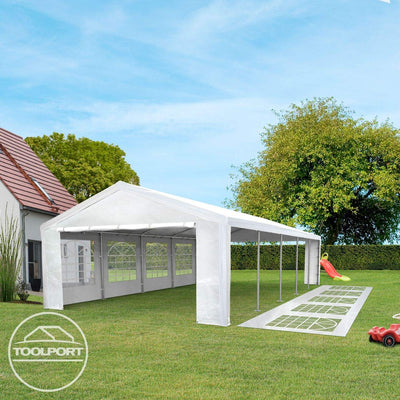 Angled view of marquee with an open side, spare window panels laid on the lawn and children's toys at the edge